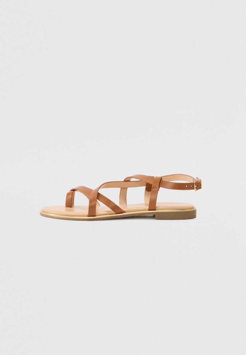 Sandales en cuir tanné avec plusieurs brides croisées, bout ouvert, semelle plate et bride de cheville réglable avec une petite boucle en métal.