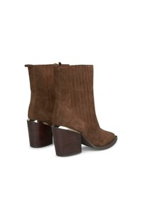 Botas de ante marrón hasta el tobillo con un tacón de madera oscura, grueso y texturizado; costuras verticales acentúan los lados y tienen un diseño de punta redondeada.