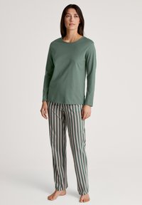Groene langemouwshirt gecombineerd met groen en wit gestreepte broek. Beide zijn gemaakt van zachte stof, wat zorgt voor een losse pasvorm en comfortabel ontwerp.