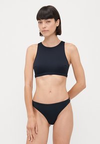 Čierny bikini set s plavkami s vysokým výstrihom a nohavičkami s nízkym pásom. Vyrobený z hladkej, elastickej látky s minimálnym počtom švov.