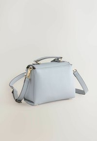 Világoskék téglalap alakú kézitáska felső fogantyúval, állítható vállpánttal és aranyszínű szerelékkel, egyszínű háttéren.