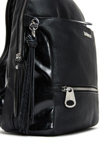 Sac à dos en cuir noir avec finition texturée, quincaillerie argentée et détail de pompon. Comprend une poche zippée sur le côté et une fermeture éclair avec accent poli.