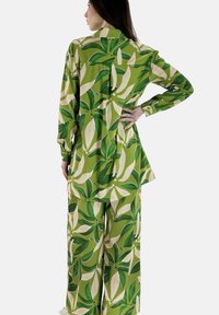 Completo di camicia e pantaloni con motivo a foglie verdi, realizzato in tessuto leggero. Maniche lunghe, colletto, con una vestibilità comoda e un design fluido.