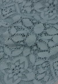 Blauwe kantstof met ingewikkelde bloemmotieven en open weefsels, die fijne details en een delicate textuur toont.