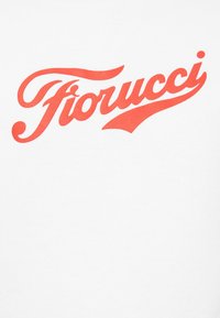 T-shirt branca com um ousado logo em cursivo vermelho "Fiorucci" atravessando o peito. O design possui uma textura suave e uma tipografia clara.