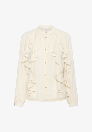 Blouse crème avec un devant froncé et des boutons dorés. Dispose de manches longues avec des poignets froncés et un col arrondi. Tissu lisse et léger.