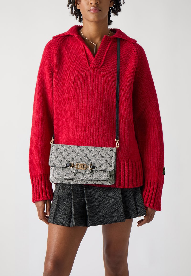Gray patterned crossbody bag with a gold clasp, worn over a red oversized sweater and a black plaid skirt; textured knit detail visible.