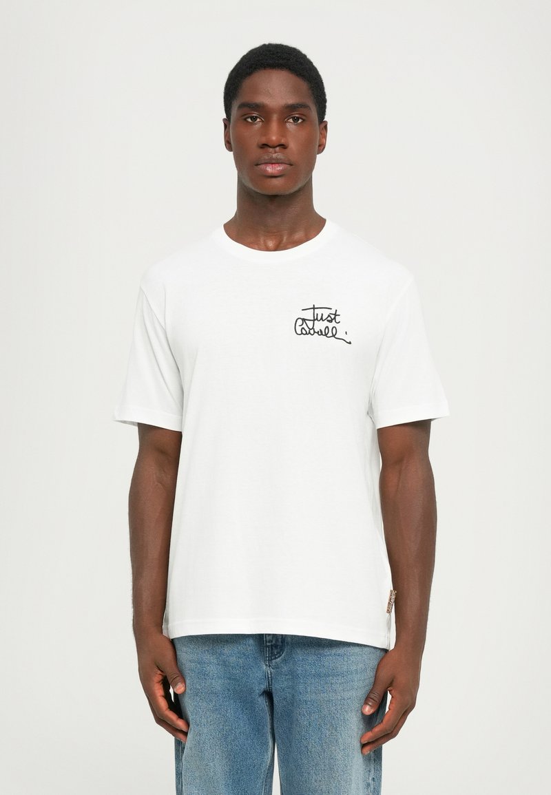 Tricou alb din bumbac, cu mâneci scurte, guler rotund, având inscripționat de mână în negru "Just". Croi casual, textură fină, etichetă pe lateral.