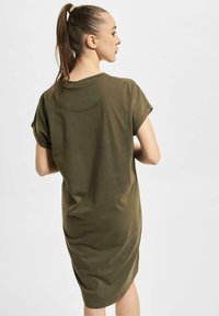 Oliwkowa sukienka t-shirt z krótkim rękawem, o luźnym kroju, okrągłym dekolcie i długości do połowy łydki. Miękki materiał z minimalną ilością szwów i detali.