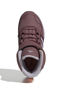 Brown athletic shoe with a textured upper, lace closure, padded collar, and white accents. Features a loop at the heel for easy wear.