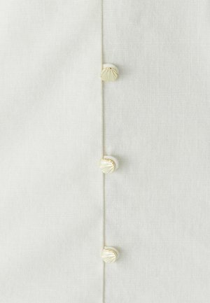 Bílá lněná tkanina s třemi ozdobnými knoflíky s texturovaným vzorem mušle podél jedné strany, zdůrazňující jemné detaily řemeslné práce.