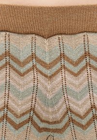 Πλεκτό ύφασμα με σχέδιο ψαροκόκαλο σε αποχρώσεις μπεζ, ανοιχτού μπλε και καφέ, με κάθετες ρίγες με τρύπες και καφέ ζωνάρι με πλεκτή υφή.