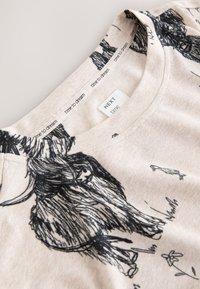 Chemise beige clair avec une impression de taureau noir style croquis, bande intérieure du col répétant « time to dream » et étiquette indiquant « NEXT time ».