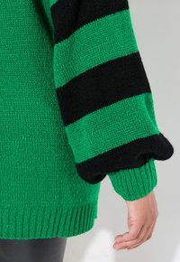 Maglione lavorato a maglia a righe verdi e nere con una vestibilità comoda. Presenta polsini e orlo a costine, evidenziando i filati testurizzati.