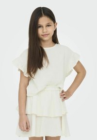 Warstwowa sukienka w kremowym lnie z krótkimi, rozkloszowanymi rękawami. Posiada marszczoną talię oraz miękką, lekką strukturę.