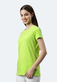 T-shirt a maniche corte, con collo rotondo, in tessuto di cotone verde brillante, caratterizzato da una silhouette aderente e una superficie liscia.