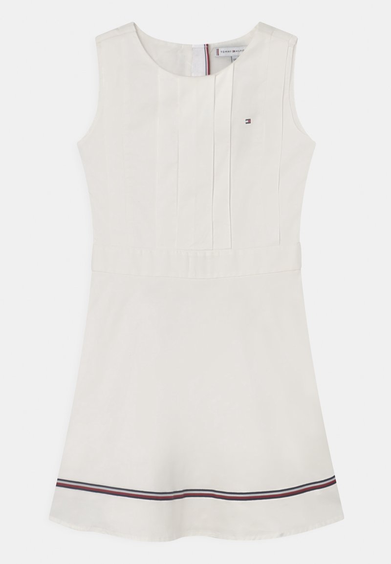 Vestido sin mangas de color blanco en corte A con frente plisado, pequeño logo bordado en el pecho, y franjas rojas, blancas y marinas cerca del dobladillo.