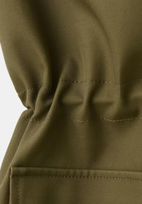 Sezione di tessuto verde oliva con cuciture elastiche arricciate e cuciture visibili, che mostra texture e pieghe in vista ravvicinata.