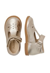 Zapatos metálicos dorados para niños pequeños con detalles cortados, diseño de tira en T, parte superior de cuero suave y suela de goma. Correa ajustable para un ajuste seguro.