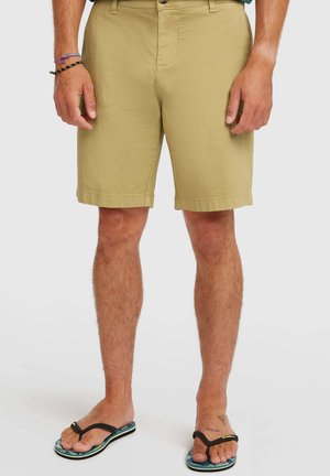 Béžové šortky z mäkkej tkaniny s plochým predným dielom, pútkami na opasok a vyhrnutými lemami. Kombinované s čierno-modrými žabkami.