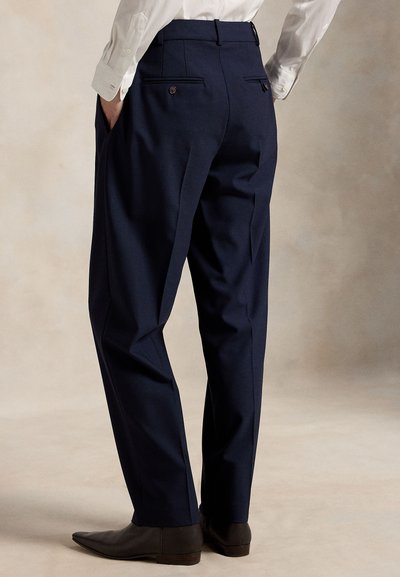 Navy blue tailored trousers with a flat front, side pockets, and back pockets with buttons; textured fabric and slim fit.