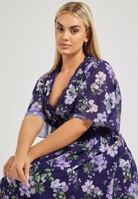 Kukallinen kimono purppuranvärisestä läpikuultavasta kankaasta, jossa on V-pääntie, pitsikoristelu ja lyhyet hihat, koristeltu erilaisilla kukkakuoseilla.