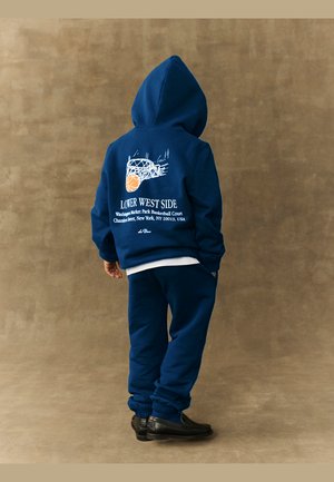 Navy blue sweatshirt and pants set, featuring a hood, elastic cuffs, and a basketball graphic on the back. Soft texture, casual fit.