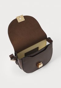 Sac à main en cuir marron avec un rabat incurvé, fermoir en or, et un intérieur texturé. Comprend un compartiment unique et une bandoulière.