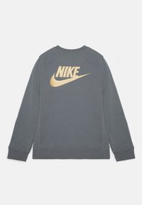 Sweat-shirt gris avec un logo Nike doré bien visible dans le dos, doté de poignets côtelés et d'un col rond classique. Texture douce en mélange de coton.
