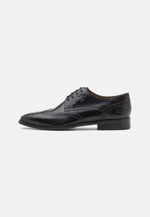 Zwarte lederen oxford schoen met brogue detailing, vetersluiting, spitse neus en een platte, lage hak. Gladde textuur met een gegrift logo.