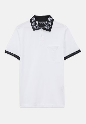 Biela polokošeľa s krátkym rukávom a čiernymi vzorovanými golierom a manžetami, predná vrecko a značka Versace Jeans Couture na golieri a manžetách.