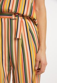 Bunt gestreiftes Outfit in Pfirsich, Grün, Gelb und Marineblau. Glatter Stoff mit einem Taillengürtel und einer lockeren Passform.