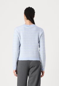 Pull tricoté bleu clair avec un motif à carreaux, texture douce, poignets et ourlet côtelés, doté d'un col rond et d'une silhouette ajustée.