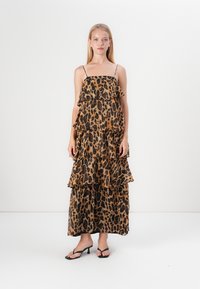 Maksi haljina s leopard uzorkom, nabranim slojevima, podesivim tankim naramenicama i laganom tkaninom. Paleta boja uključuje nijanse smeđe i crne.