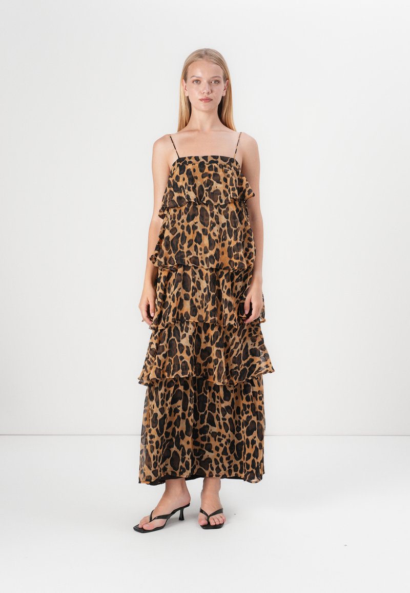 Maksi haljina s leopard uzorkom, nabranim slojevima, podesivim tankim naramenicama i laganom tkaninom. Paleta boja uključuje nijanse smeđe i crne.