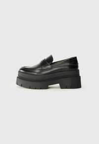 Black leather loafers with a chunky platform sole. Rounded toe, front seam detail, and subtle stitching accents. Flat, textured outsole.