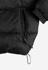 Czarna ocieplana kurtka z kieszenią na zamek, teksturowaną tkaniną, elastycznymi mankietami i sznurkiem do regulacji.