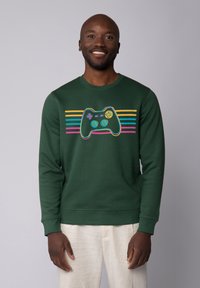 Green sweatshirt with a video game controller graphic in bright colors, featuring horizontal stripes in pink, yellow, and blue.