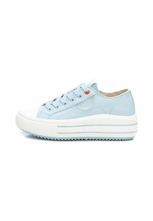 Zapatilla de lona azul claro con suela de goma blanca, que presenta un diseño texturizado y cordones azules. Incluye un acento naranja en el ojal.
