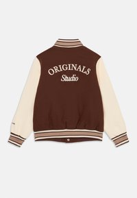 Hnedo-krémová varsity bunda, s výšivkou "ORIGINALS Studio" na zadnej strane, rebrovaným golierom a manžetami, a so pruhovaným lemovaním.