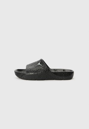 Melnas slides čības ar teksturētu virsmu, kurām ir paaugstināts logotips un kontūrēta zole. Materiāls izskatās izturīgs un elastīgs.