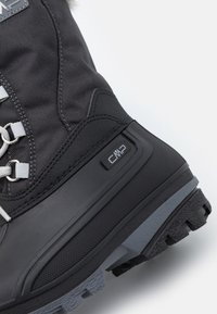 Botte d'hiver noire en tissu texturé et caoutchouc avec lacets blancs, embout renforcé et un accent gris sur la semelle ; logo CMP visible.