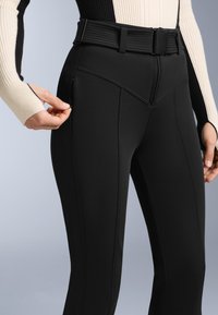 Fekete sport leggings, texturált derékpánttal, cipzáras zsebbel és ferde varratokkal, a kényelem és a funkcionalitás érdekében tervezve.