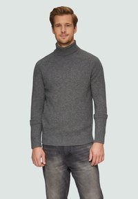 Pull en col roulé gris en tissu texturé, avec une coupe ajustée et des poignets côtelés, associé à un jean gris foncé.