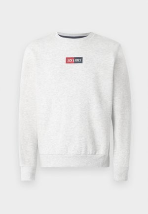 Šedá mikina s kulatým krkem, ribovanými manžetami a lemem, s červeným a námořnickým obdélníkovým logem na hrudi. Měkká textura látky.