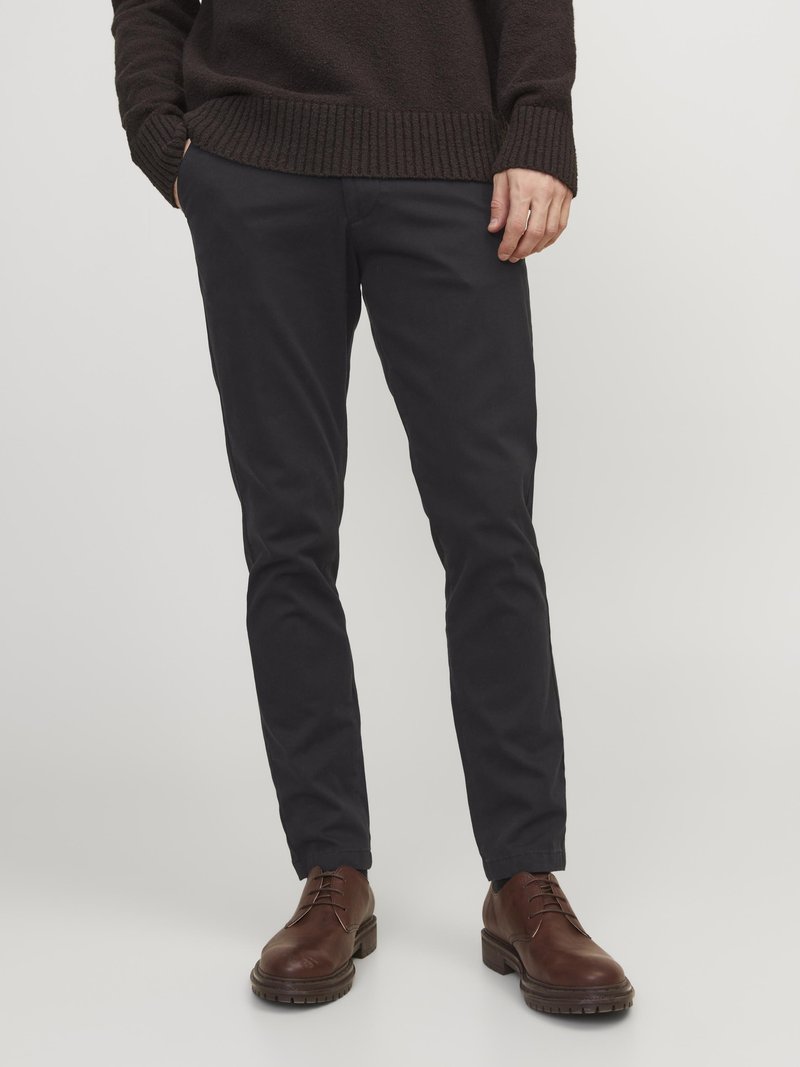 Dark navy chino pants with a slim fit, featuring a smooth texture, and paired with brown leather shoes. Gathered at the ankles.