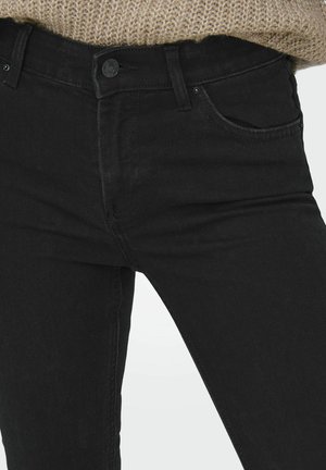 Crne traperice od denima s prilagođenim dizajnom, stilom s pet džepova i metalnim kopčanjem. Tkanina ima glatku teksturu s blagim rastezljivim svojstvima.