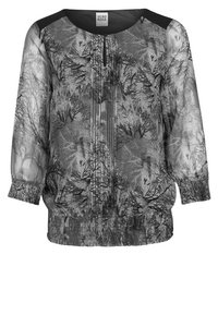 Przezroczysta czarna bluzka z wzorem gałęzi drzew, z dekoltem w kształcie klucza, rękawami o długości trzy czwarte oraz marszczonym dołem dla zwiększenia tekstury.