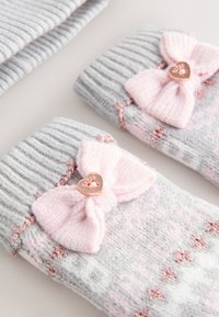 Grau-pinke gestrickte Socken mit einer großen pinkfarbenen Schleife und einem herzförmigen Knopf, mit einer gerippten Struktur und dezenten Akzenten.