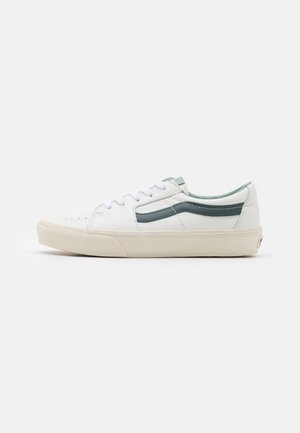 Sneaker bianco in pelle con finitura testurizzata, dettagli verde e lacci bianchi. Presenta una suola in gomma color crema e dettagli di cucitura.